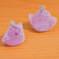 Macro shot of two pink flocked bird charms with metal rings on a wooden texture background - Purple