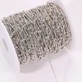 Macro shot of silver plated copper snake chain with small beads wound on a white spool - Silver