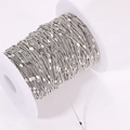 Detail of silver plated copper chain with small heart charms wound on a white plastic spool - Silver