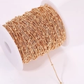 Detail of gold box chain with beads on a white spool for DIY jewelry making - Gold