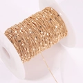 Detail of gold-plated copper heart link chain wrapped on a white plastic spool for DIY jewelry - Gold