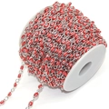 Detail of red resin evil eye beads connected by polished silver copper chain links on a spool - Red Eye Silver Chain