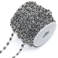 Close-up of black and white evil eye bead chain on white spool for DIY jewelry making - Black Eye Silver Chain