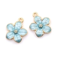 Detailed macro view of cherry blossom charms with blue enamel petals and golden edges - Blue