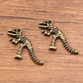 Vintage bronze dinosaur skeleton alloy charms for DIY jewelry making on wooden surface - Antique Bronze