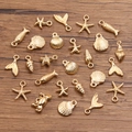 Goldene Meeres-Schmuckanhänger mit Seesternen und Muscheln auf rustikalem Holzhintergrund - Meereslebewesen Zufällige Kollektion