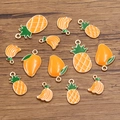 Macro shot of KC gold enamel tropical fruit pendants on a dark wood background - Orange