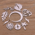 Detailed flat lay of diverse stainless steel DIY jewelry pendants on a wood surface - Steel