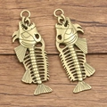 Paar vintage bronzen visgraat hangers op een rustieke houten achtergrond - Brons