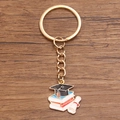 Detail of graduation keychain featuring a black mortarboard, books, and scroll on wood - Style 8 (21X25mm)