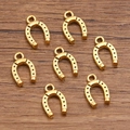 Set of 7 gold-colored metal horseshoe charms with dotted texture on wooden background - No.1 Antique Gold