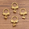 Lot de quatre breloques nœuds et cloches dorées pour bijoux DIY sur fond de bois rustique - Bague Tissée (1601 Couleur Or)