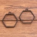 Pair of hexagonal black metal open bezel charms for DIY jewelry making on wood background - Hexagon