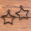 A pair of star-shaped black alloy pendant frames for DIY jewelry on wooden background - Pentagram