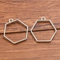 Set of two silver hexagonal hollow frames for DIY jewelry crafts on a wooden surface - Hexagonal Style