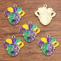 Five Mardi Gras jester mask pendants in purple, green, and gold enamel on wood surface - No.14 Green Purple Drama Mask Pendant