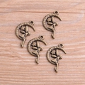 Detailed macro view of four antique bronze angel moon alloy charms on wooden surface - Antique Bronze