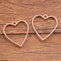 Two rose gold hollow heart pendants for DIY jewelry making on a wooden background - Heart Style / Rose Gold