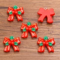 Five pieces of red resin Christmas bow charms with green leaves on wooden background - Size 9