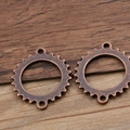 Detail van vintage bronzen tandwielhangers met dubbele lussen op rustieke houten achtergrond - Roodbrons 22 G