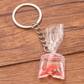 Realistic goldfish in a clear water bag pendant on a silver keychain over a wood background - Red Carp