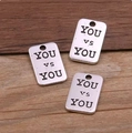 Gros plan de pendentifs rectangulaires en alliage argenté vintage avec gravure YOU vs YOU - Style YOU vs YOU (20E11) / Argent antique