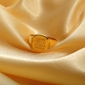 Gros plan d'une bague dorée gravée LOVE EACH OTHER MORE sur un tissu en soie fine - US 7 / LOVE EACH OTHER MORE