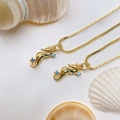 Detailed close-up of golden seahorse pendants with blue zircon on white shells - Gold Seahorse Necklace (25110216)