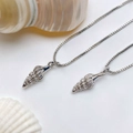 Detailed view of silver seashell pendant with box chain on a minimalist white background - Silver Spiral Shell Necklace (25110216)