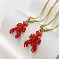 Detail of red lobster enamel pendant necklaces with gold finish on a white display - Red Lobster Necklace (25110216)