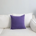 Coussin carré violet avec bordure à pompons blancs sur un canapé en tissu blanc - 45x45cm / Violet avec Pompons Blancs