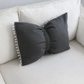 Cuscino decorativo nero a forma di fiocco con pompon bianchi su un divano - Grigio / 43x55cm