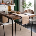 Natural jute table runner featuring dark grey pom-poms on a dark wooden table - Natural Jute With Gray Pom-poms