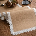 Rustic jute table runner with white lace edges on a wooden table with pine cones - Jute With Dot Lace