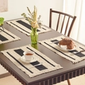 Set of four black and white striped woven placemats with fringe on a wooden table - Black Three-Stripe White Fringe Placemat
