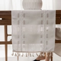 Creamy white woven table runner with tassel fringe on a wooden dining table surface - Long Runner / White