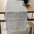 Light gray linen table runner with geometric hollow weave and cream tassels on wood table - Long Runner / Light Gray
