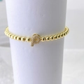 Detalle de la pulsera de cuentas doradas con colgante de letra P y cristales brillantes - Oro P