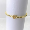 Detalle de una pulsera de cuentas de latón dorado con colgante de letra V y pavé de circón - Oro V