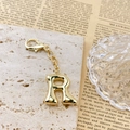 Vue macro détaillée d'un porte-clés lettre R en métal doré poli sur une pierre - Lettre R