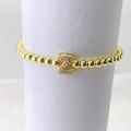 Detalle macro de pulsera de cuentas doradas con colgante de letra Z y circonitas - Oro Z