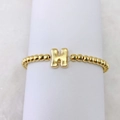 Makroansicht der 18k vergoldeten Perlenarmband mit einem großen Metall-H-Anhänger-Detail - Buchstabe H