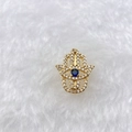Detailed macro of Hamsa hand pendant with blue stone and sparkling zircon pavé on white fur - Gold Hamsa Hand (Style 160)