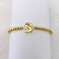 Detail eines 18k vergoldeten Perlenarmbands mit einem runden metallischen S-Anhänger - S