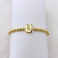 Makroaufnahme eines 18k Goldperlenrings mit poliertem Buchstaben-U-Anhänger im Detail - Buchstabe U