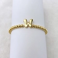 Detail eines 18k vergoldeten Perlenarmbandes mit einem markanten Buchstaben-W-Anhänger - Buchstabe W