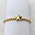 Nahaufnahme eines 18k vergoldeten Perlenarmbands mit einem polierten Sternanhänger - Pentagramm