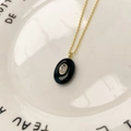 Détail d'un collier chaîne dorée avec pendentif ovale noir et pierre en zircone claire - Collier en Zircone Ovale Obsidienne (250730320700) / Pendentif avec Chaîne / Noir