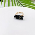 Macro shot of fish-shaped ring with green stone and golden wire wrap on a white tray - Black Onyx Look (Style D)