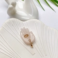 Makro-Detail von goldenem Anhänger mit gelbem Stein auf einem rosa Quarz-Halter - Rosa Offener Zirkonia-Ring (I-Stil)
